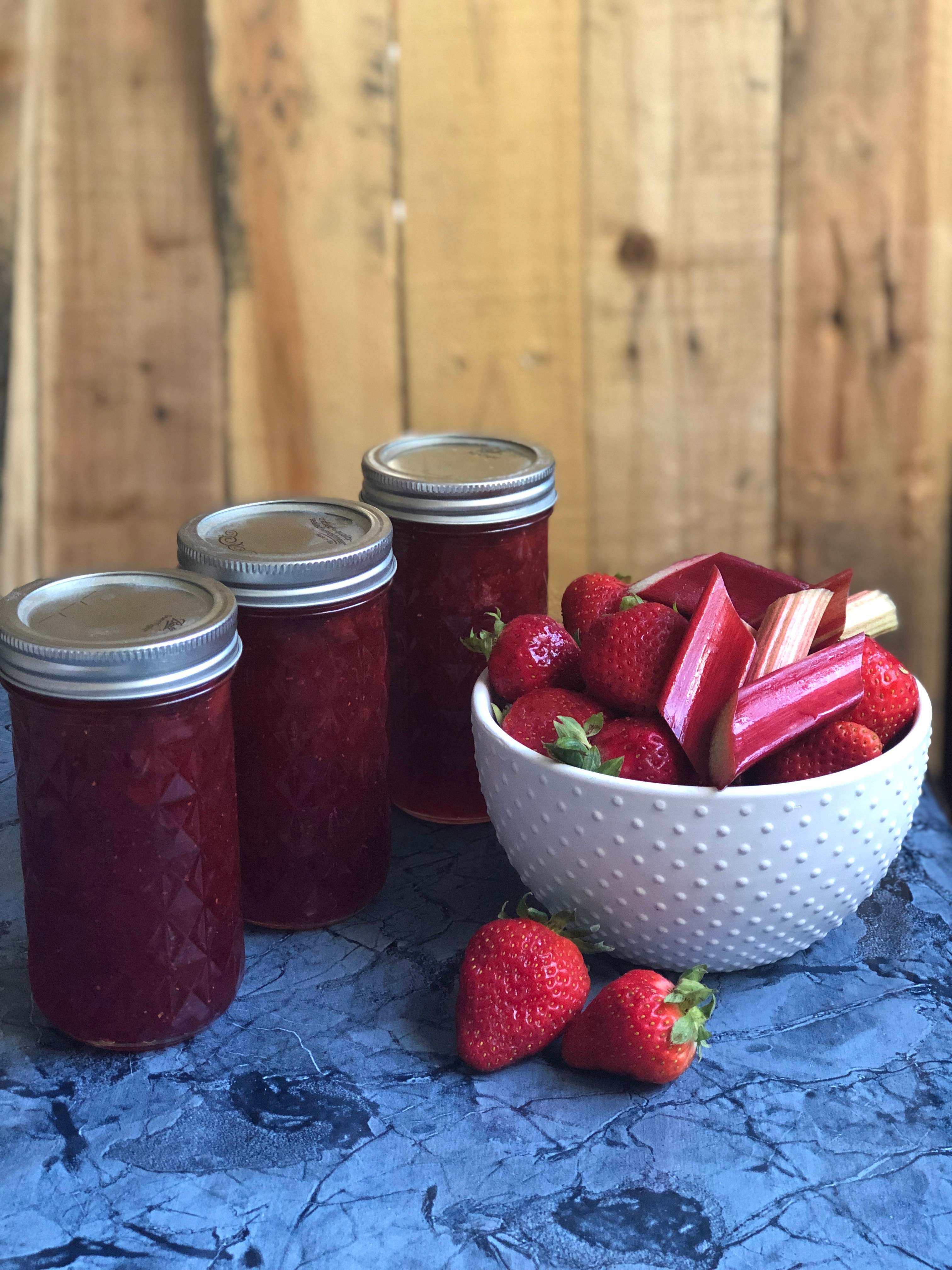jars of homemade strawberry rhubarb jam on a wooden table