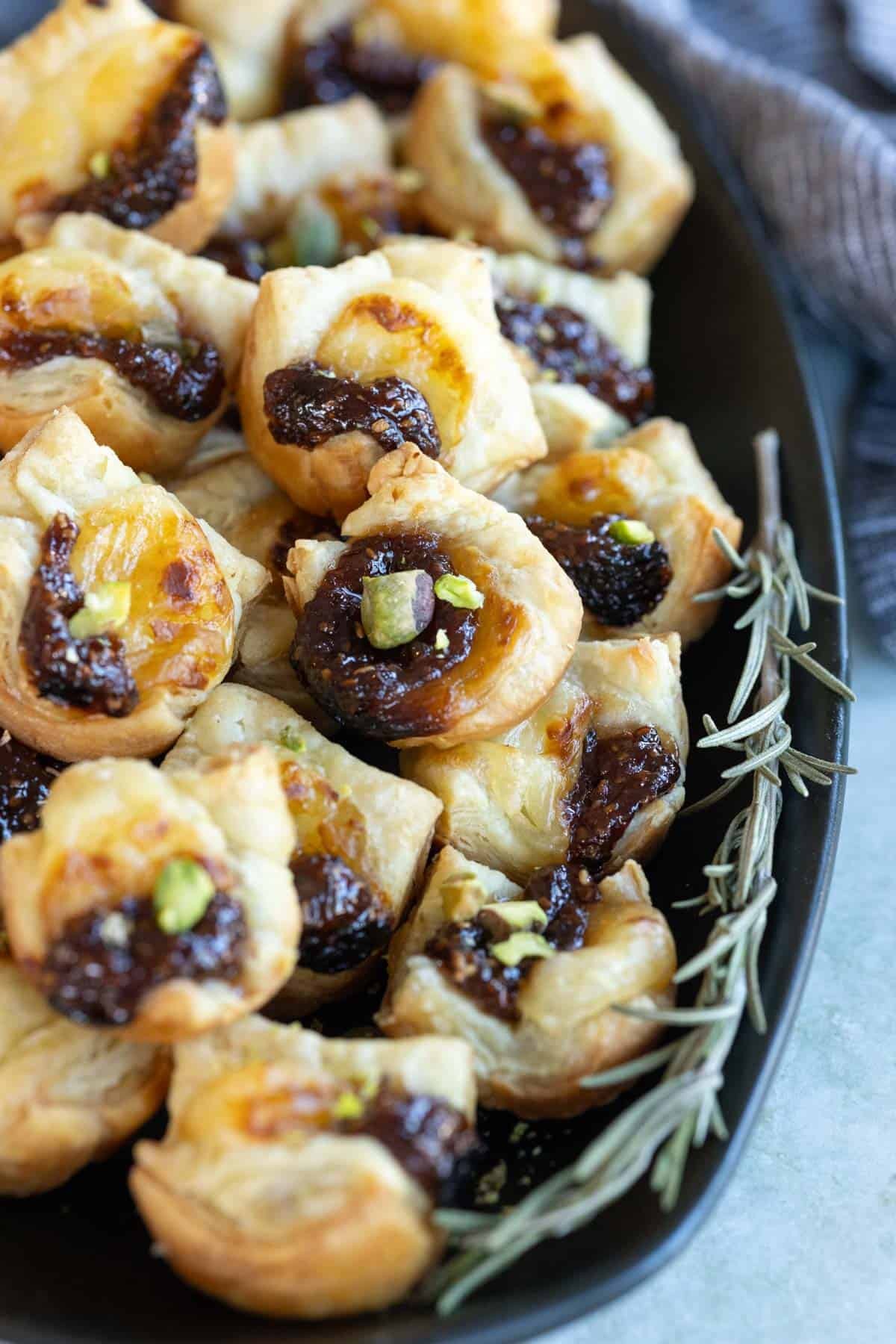 golden brown cheese stuffed pastry bites on a platter with dipping sauce, close-up, party food