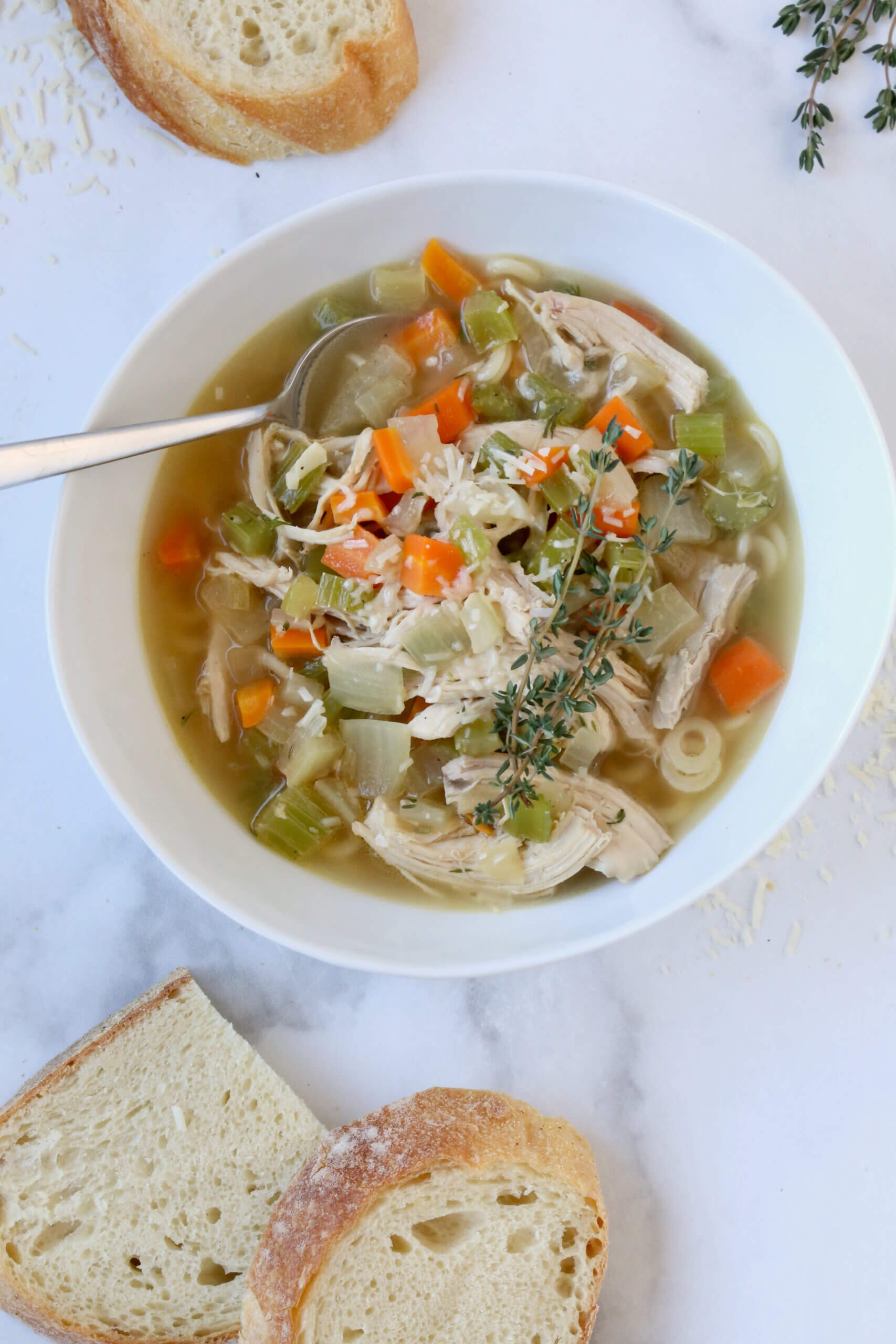 A comforting bowl of homemade chicken noodle soup with visible steam and rustic bread on the side