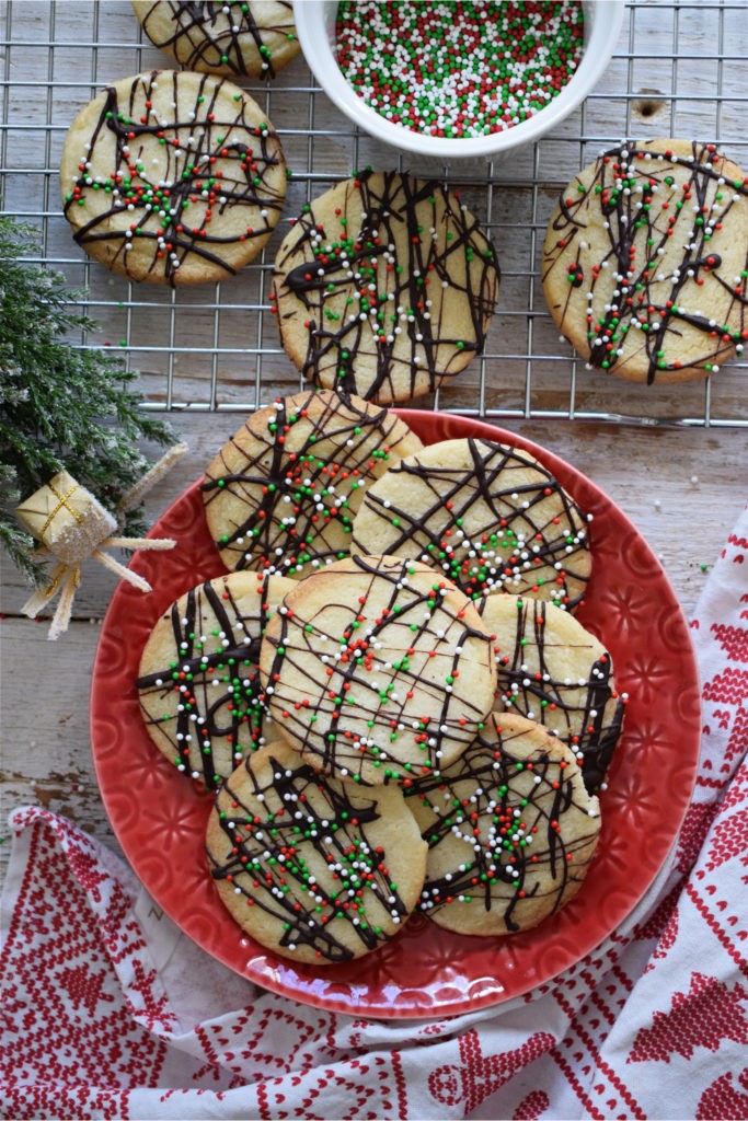 Homemade chocolate dipped shortbread cookies arranged on a cooling rack with melted chocolate drizzle