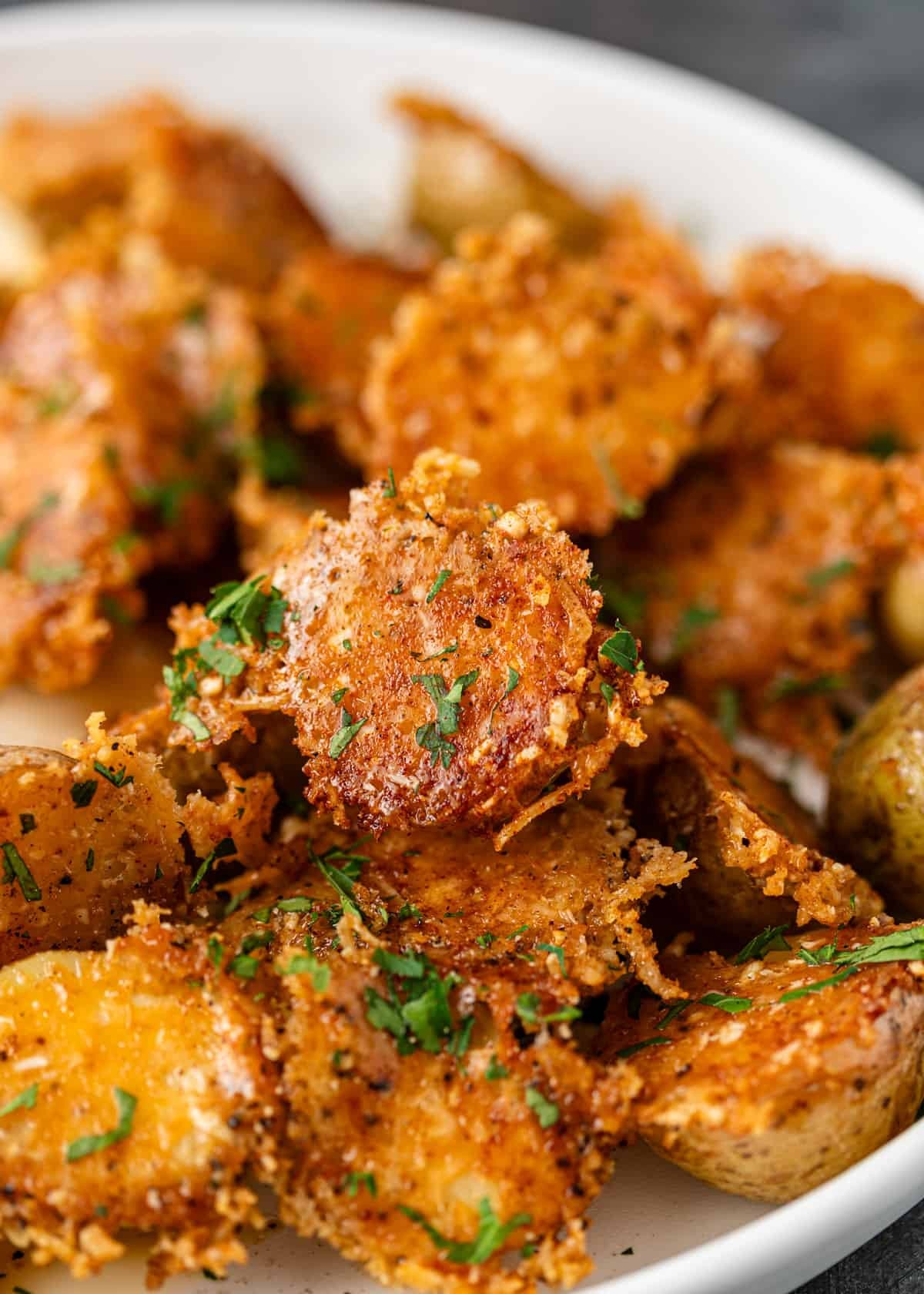Close-up of golden brown crispy parmesan roasted potatoes with fresh herbs