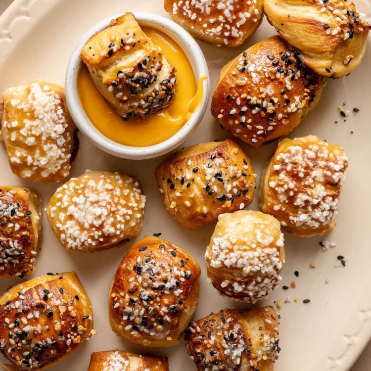 golden brown soft pretzel bites on a baking sheet with coarse salt, warm and inviting