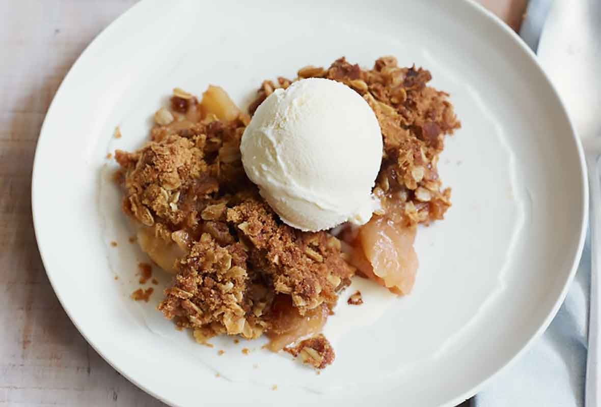 Rustic apple crumble with cinnamon crust, served warm with a scoop of vanilla ice cream, cozy autumn setting