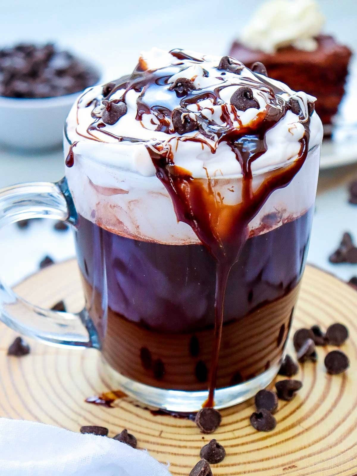 steaming rich mocha hot chocolate with whipped cream, cocoa powder dust, and coffee beans on a rustic wooden table