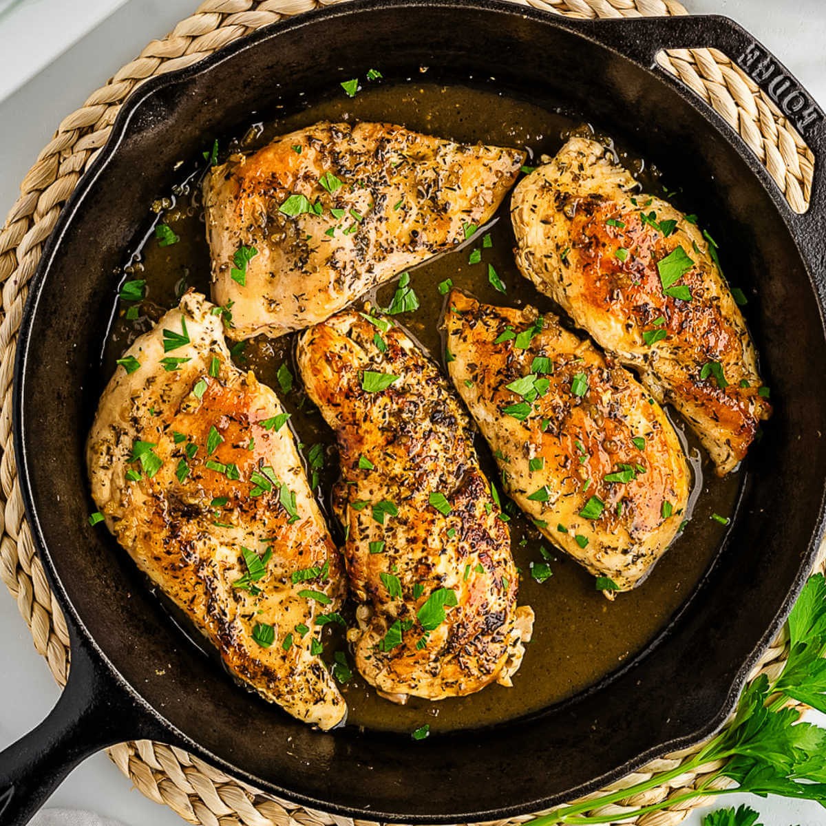 overhead shot, perfectly seared garlic butter chicken thighs in a skillet, garnished with fresh parsley, with steam rising