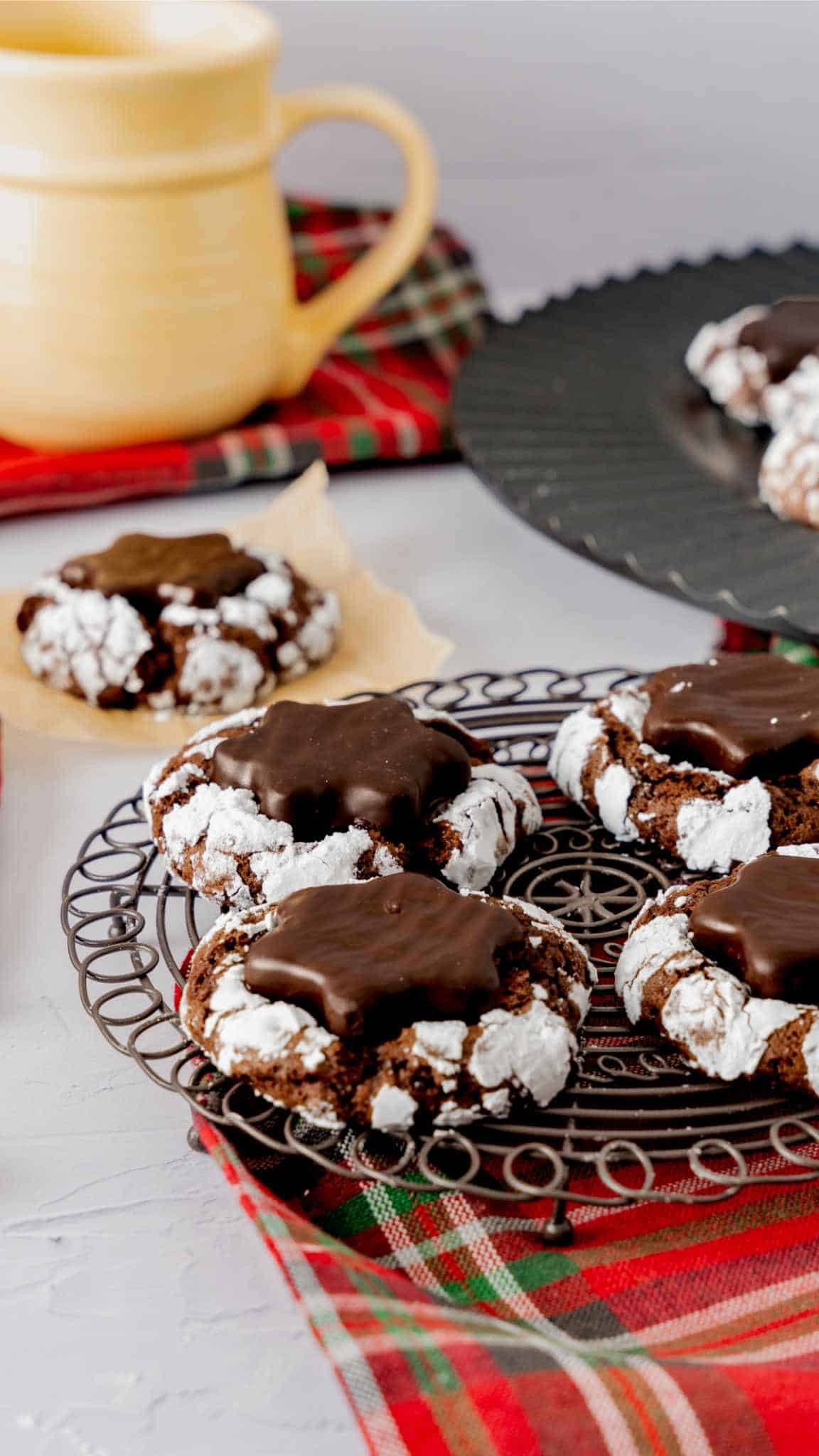 Vibrant peppermint crinkle cookies arranged on a festive Christmas platter with twinkling lights and a mug of hot cocoa in the background