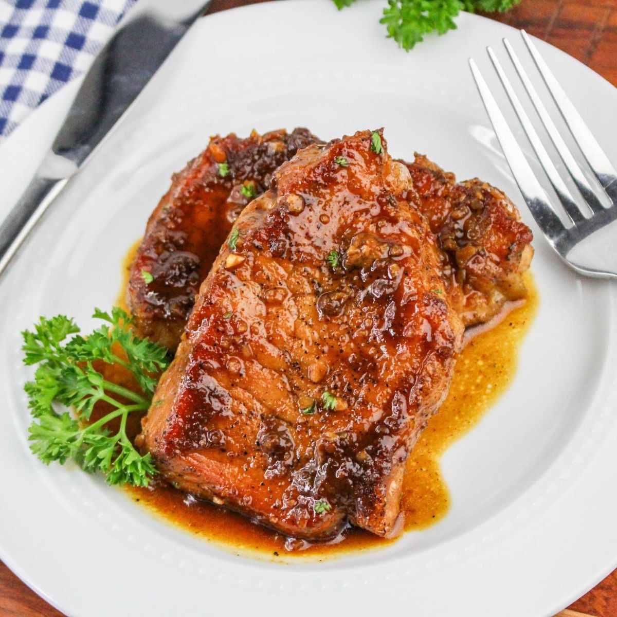 close-up of bourbon glazed pork chops on a plate, garnished with parsley
