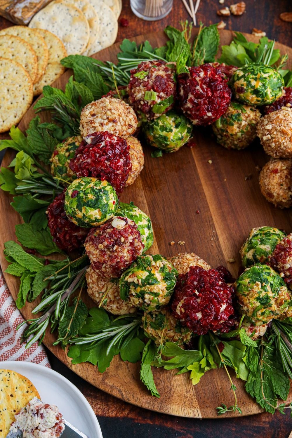 beautifully garnished herbed cheese ball with crackers on a wooden board, party appetizer