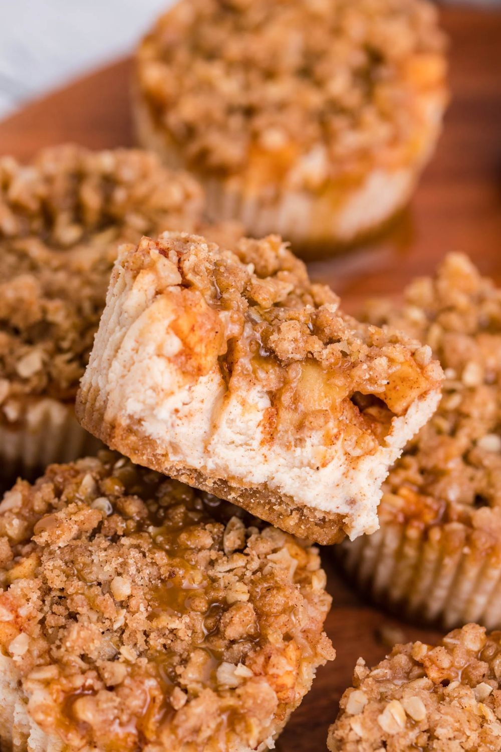 apple crumble cheesecake on a rustic wooden table with fall foliage