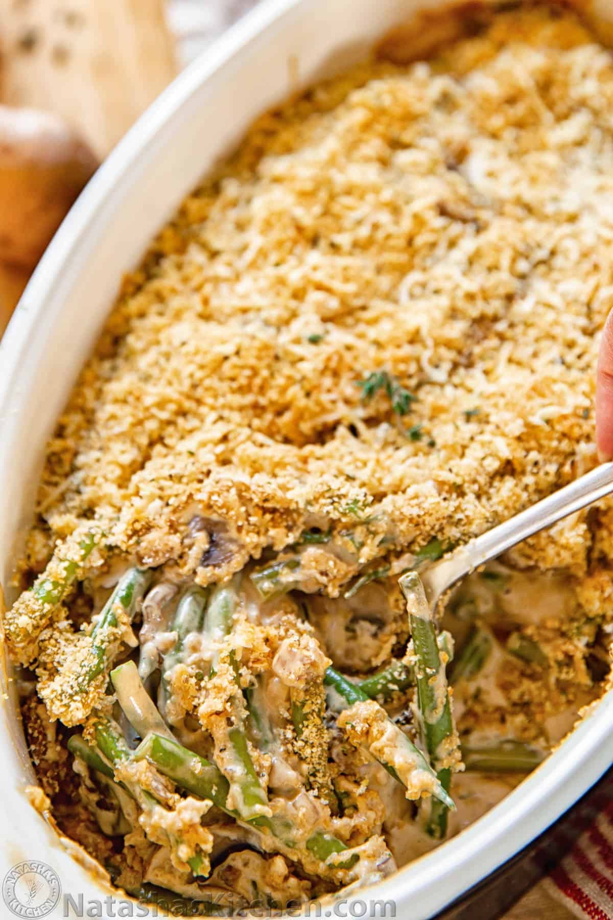 Homemade green bean casserole with golden buttery crumb topping, close up, warm light