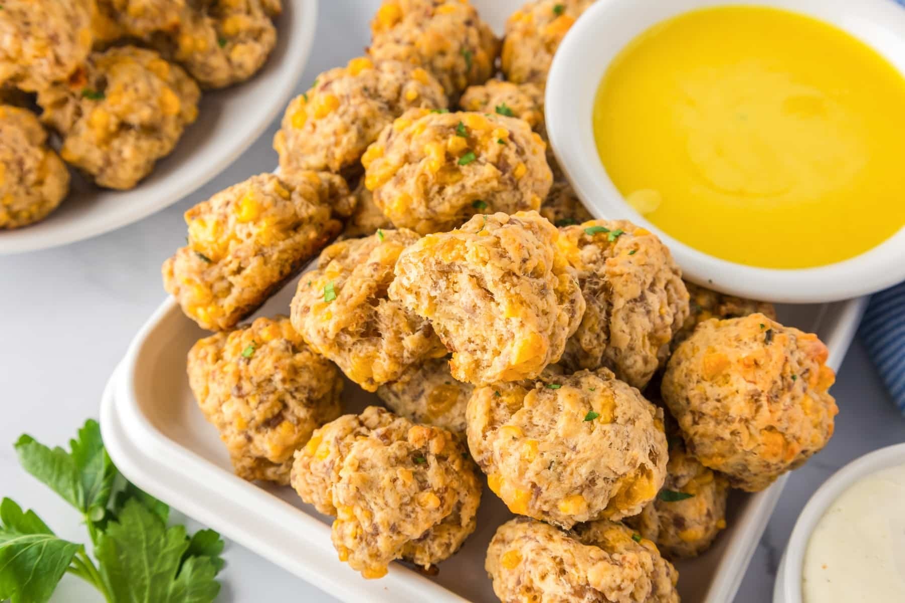 Platter of golden brown cheddar sausage balls with dipping sauce
