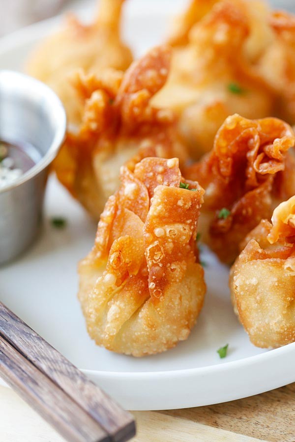 Crispy golden chicken wontons with dipping sauce, close-up, steam rising