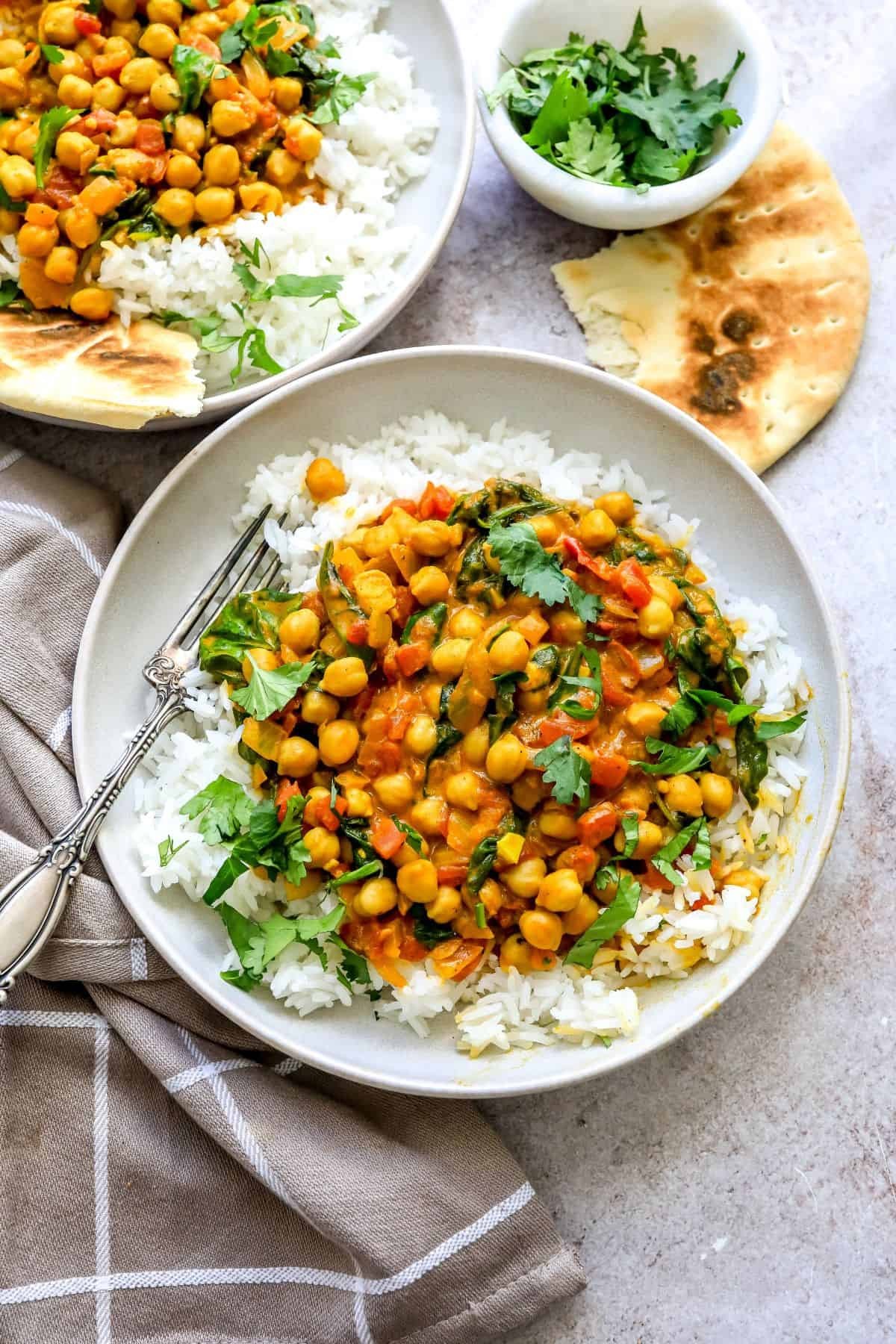 bowl of vibrant chickpea spinach curry with rice, garnished with fresh cilantro, a cozy kitchen setting