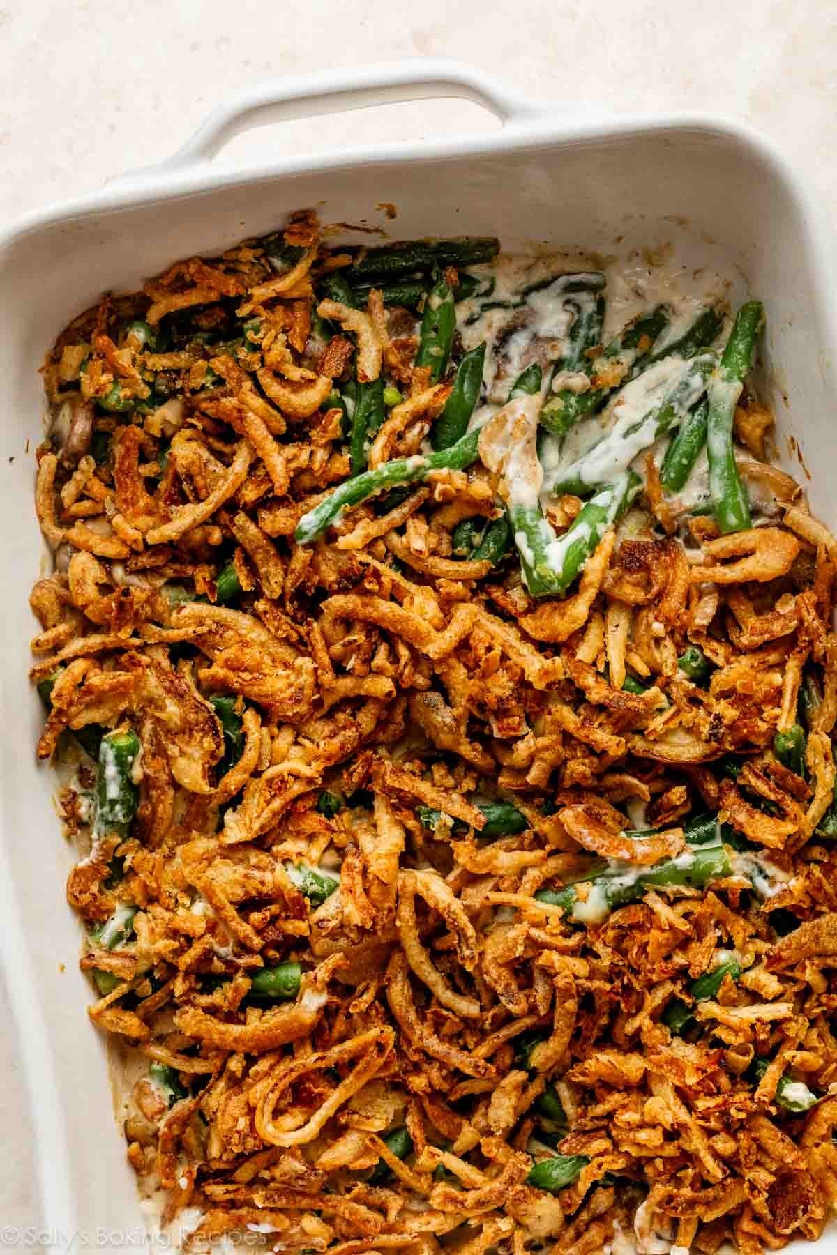 Homemade green bean casserole with creamy pepper sauce and crispy fried onions, close-up, golden brown