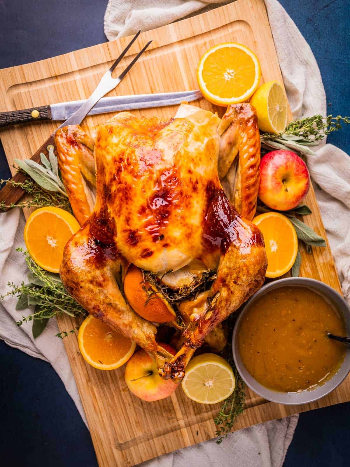 Beautifully roasted whole turkey with golden maple glaze, fresh orange slices, and herbs on a festive table setting