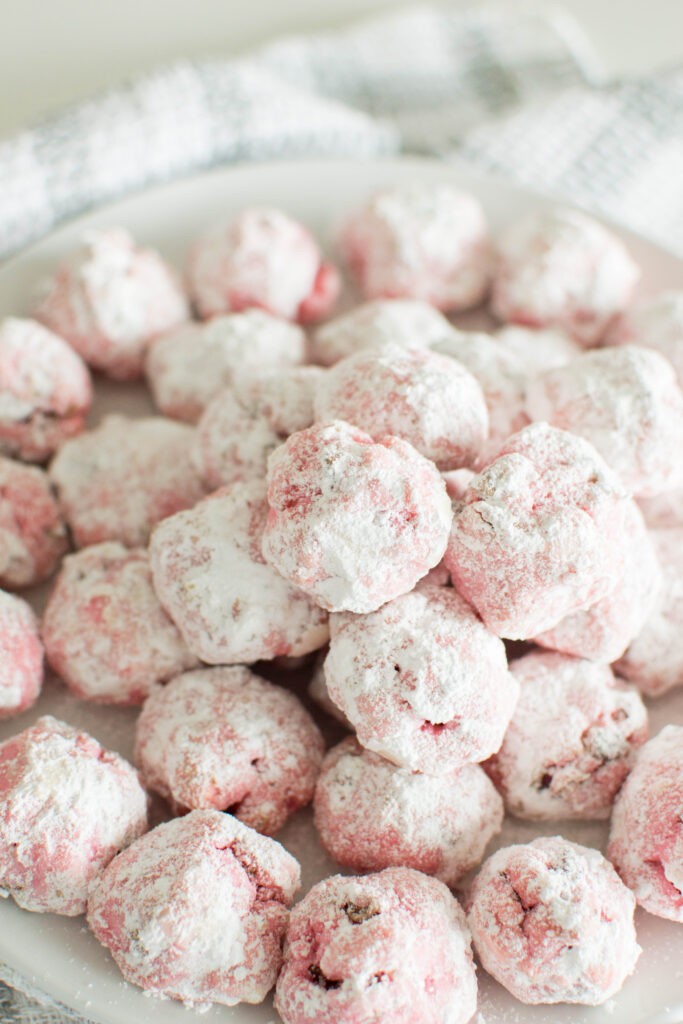close up of white chocolate raspberry snowballs dusted with powdered sugar