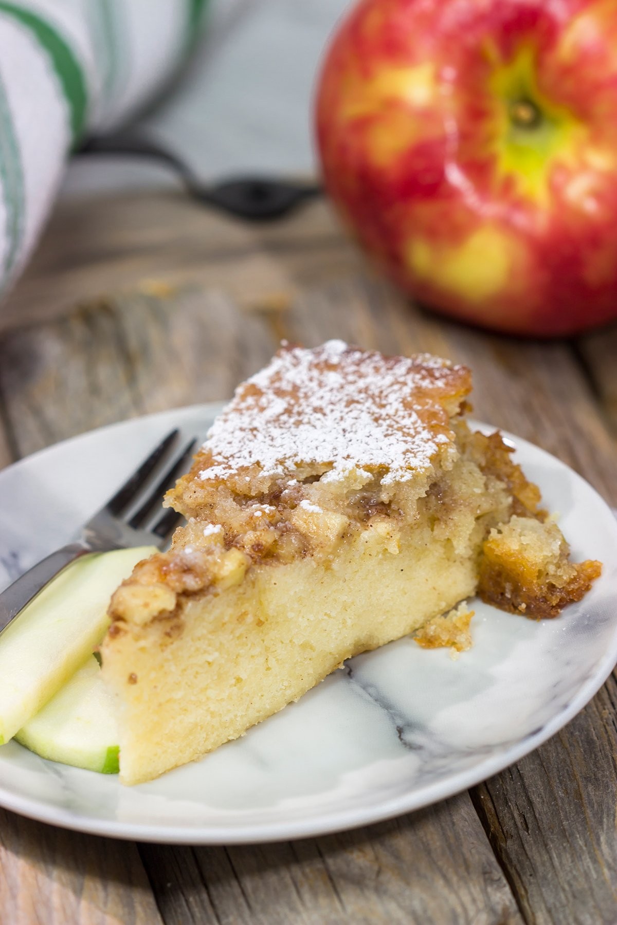 cinnamon apple cake with a slice taken out, fall leaves in the background