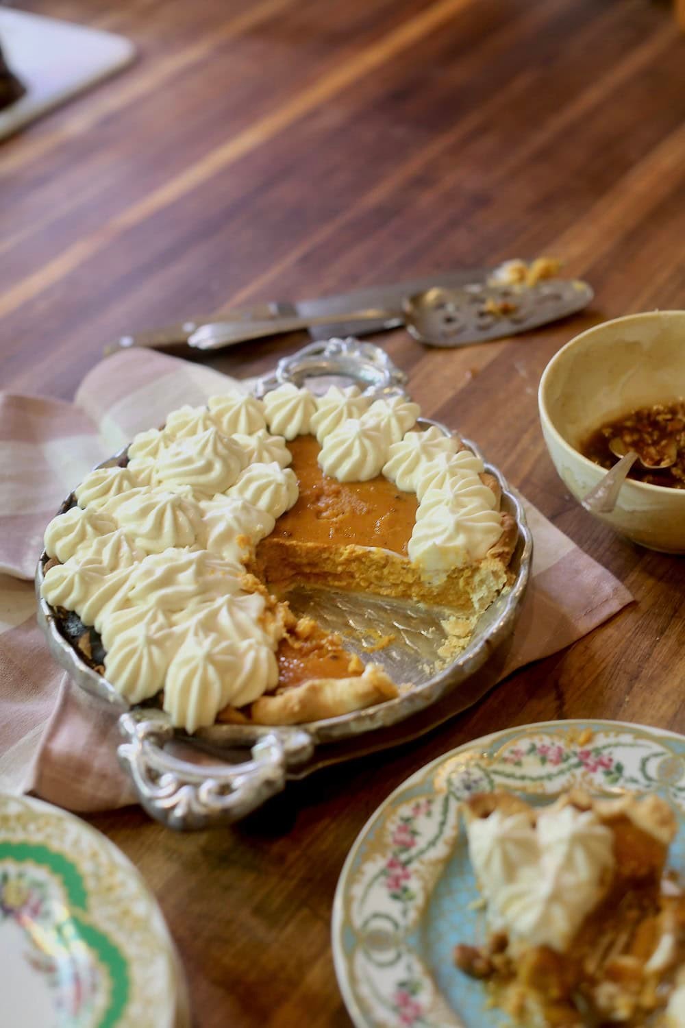 slice of silky pumpkin pie with a toasted spice crust, garnished with whipped cream and candied pecans, autumn setting, cozy ambiance