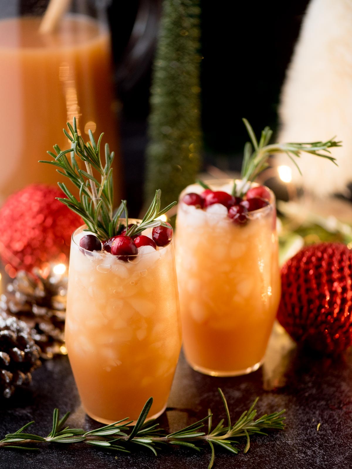 Festive non-alcoholic pineapple punch with garnishes in a large pitcher and glasses, holiday decorated background