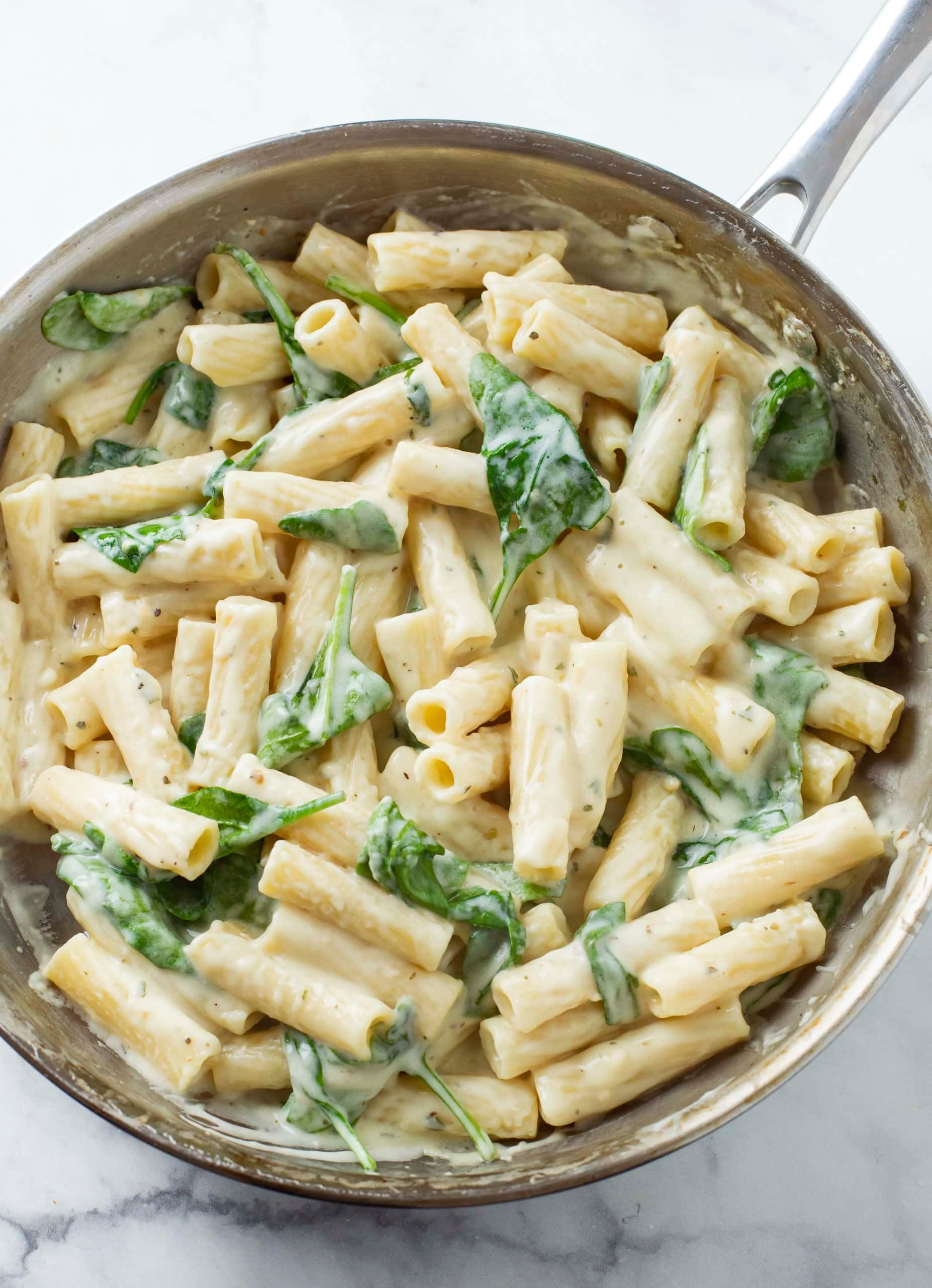 plate of creamy garlic spinach pasta with parmesan and fresh parsley, cozy kitchen setting