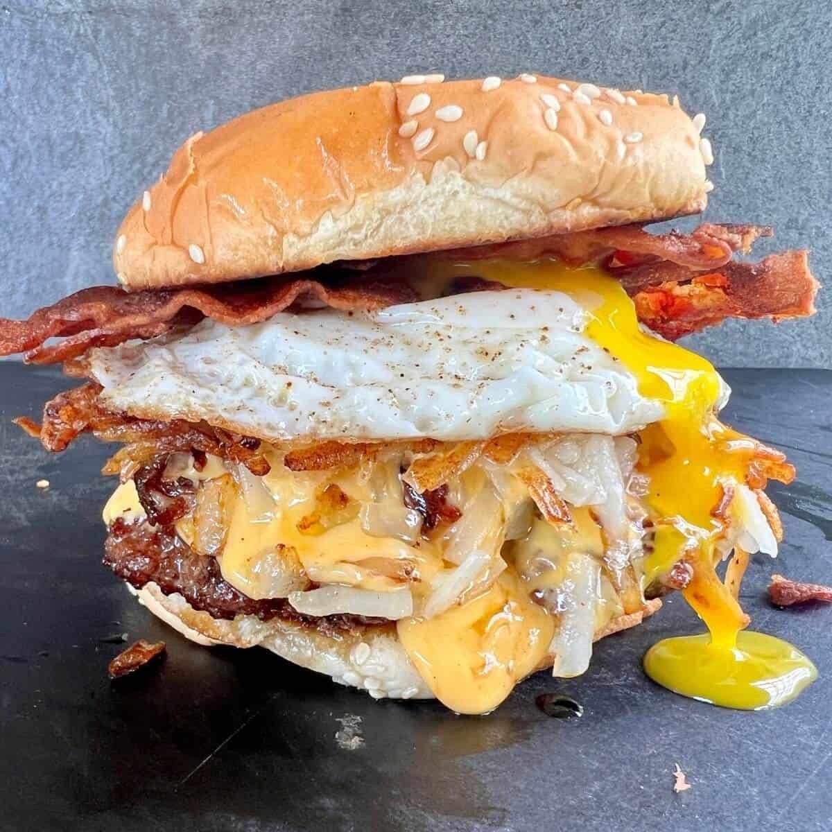 breakfast burger with egg and bacon on griddle