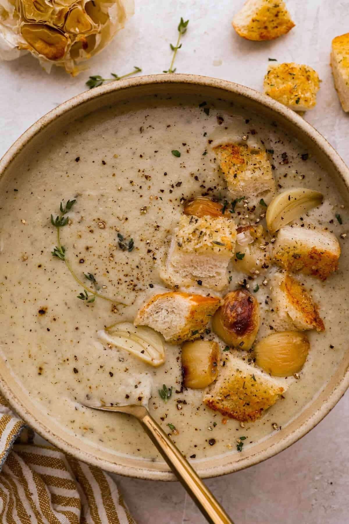 Creamy Parmesan garlic soup with croutons and fresh parsley on a rustic wooden table