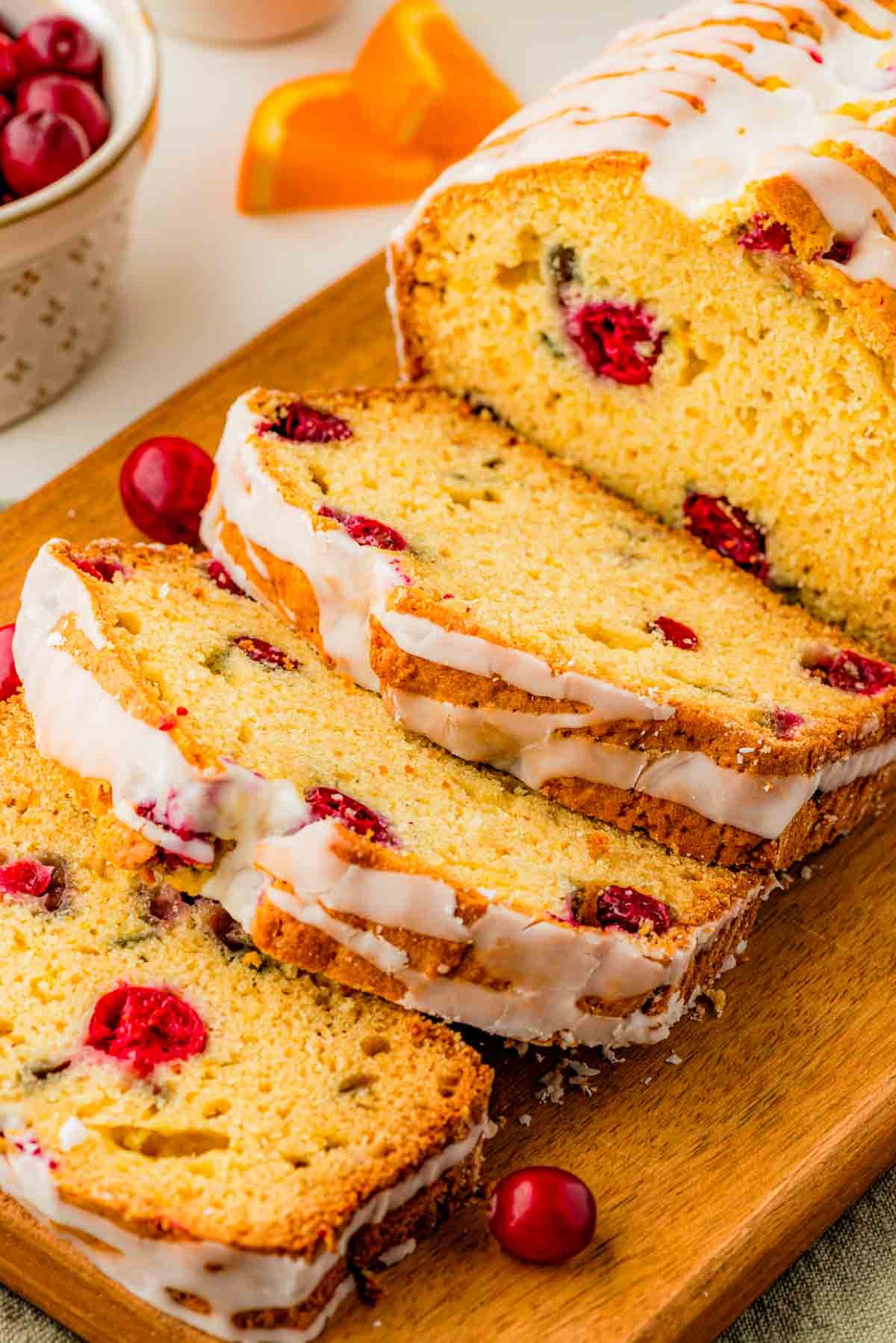 freshly baked cranberry orange bread loaf with vanilla icing drizzle, rustic kitchen background, warm lighting