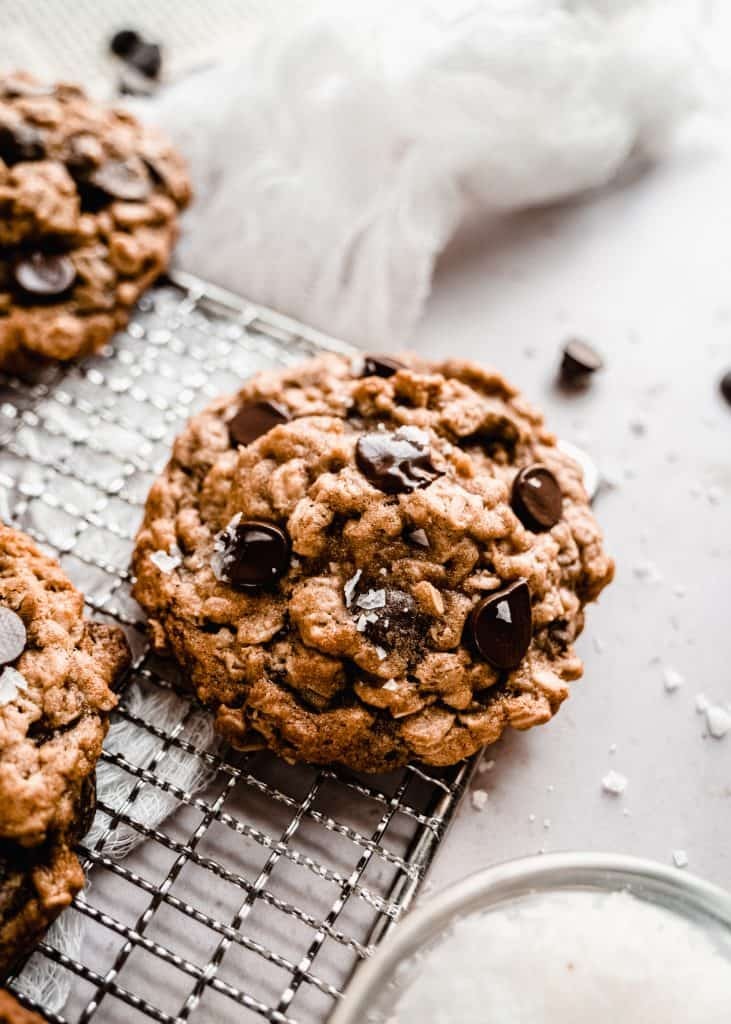 Close-up of warm, chewy oatmeal chocolate chunk cookies on a wire rack, with some chocolate still gooey