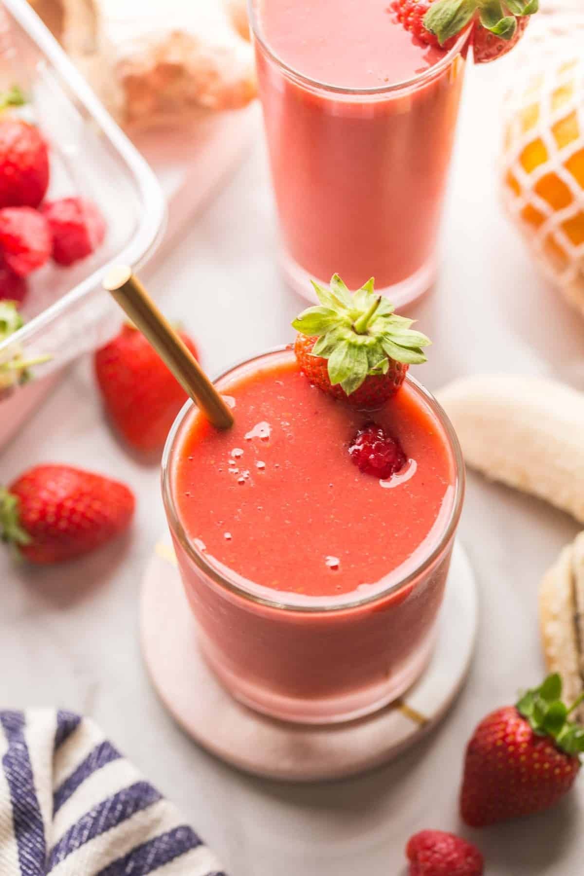 close up of a vibrant berry ginger smoothie in a glass with berries and ginger on a wooden table