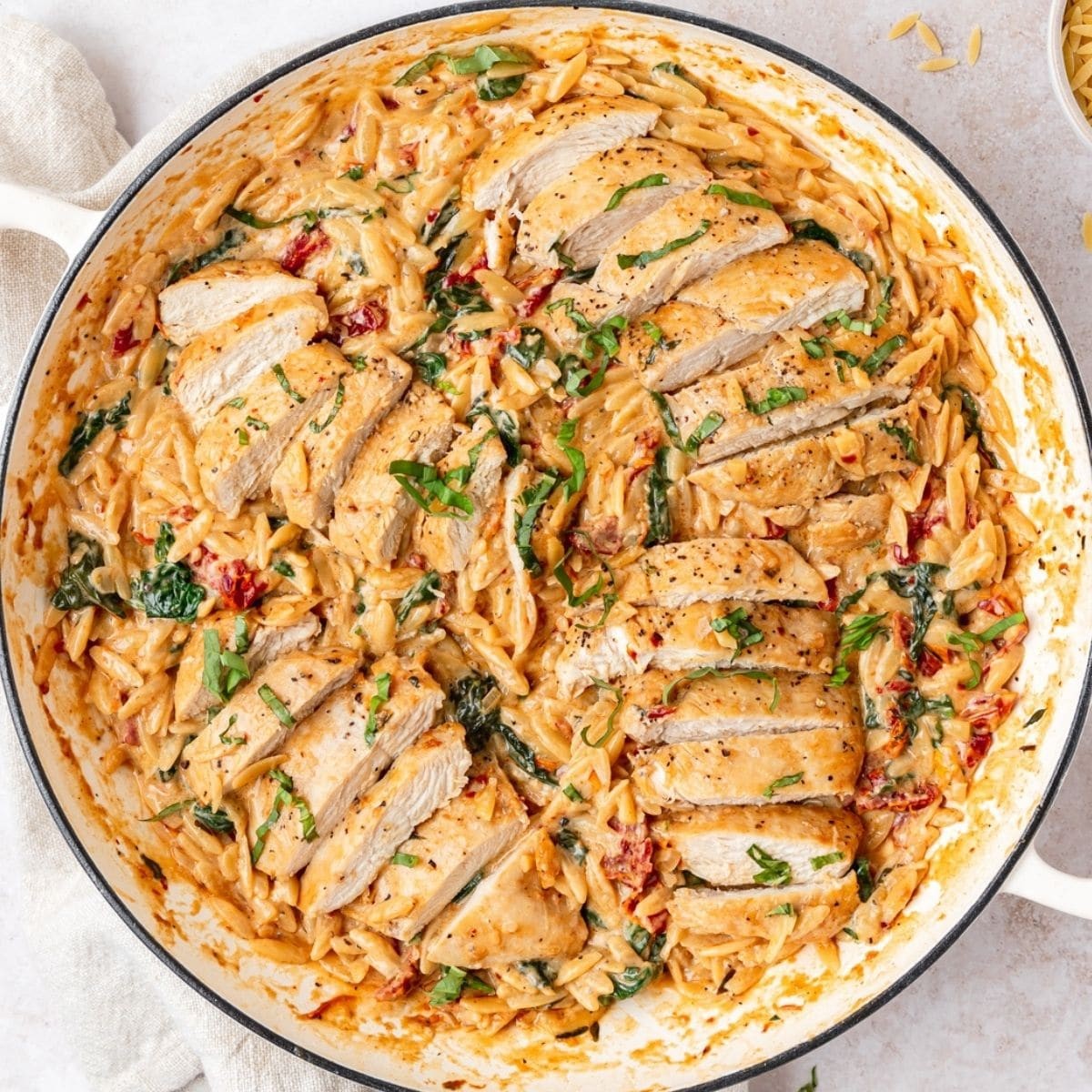 Creamy Tuscan Chicken Orzo served in a rustic bowl, garnished with fresh basil
