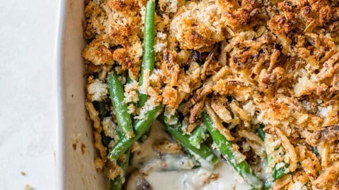Baked green bean casserole, golden brown and bubbling, garnished with fresh herbs