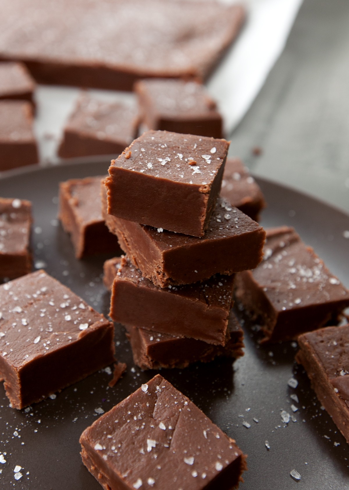 Homemade chocolate fudge squares on a wooden board, garnished with a sprinkle of sea salt