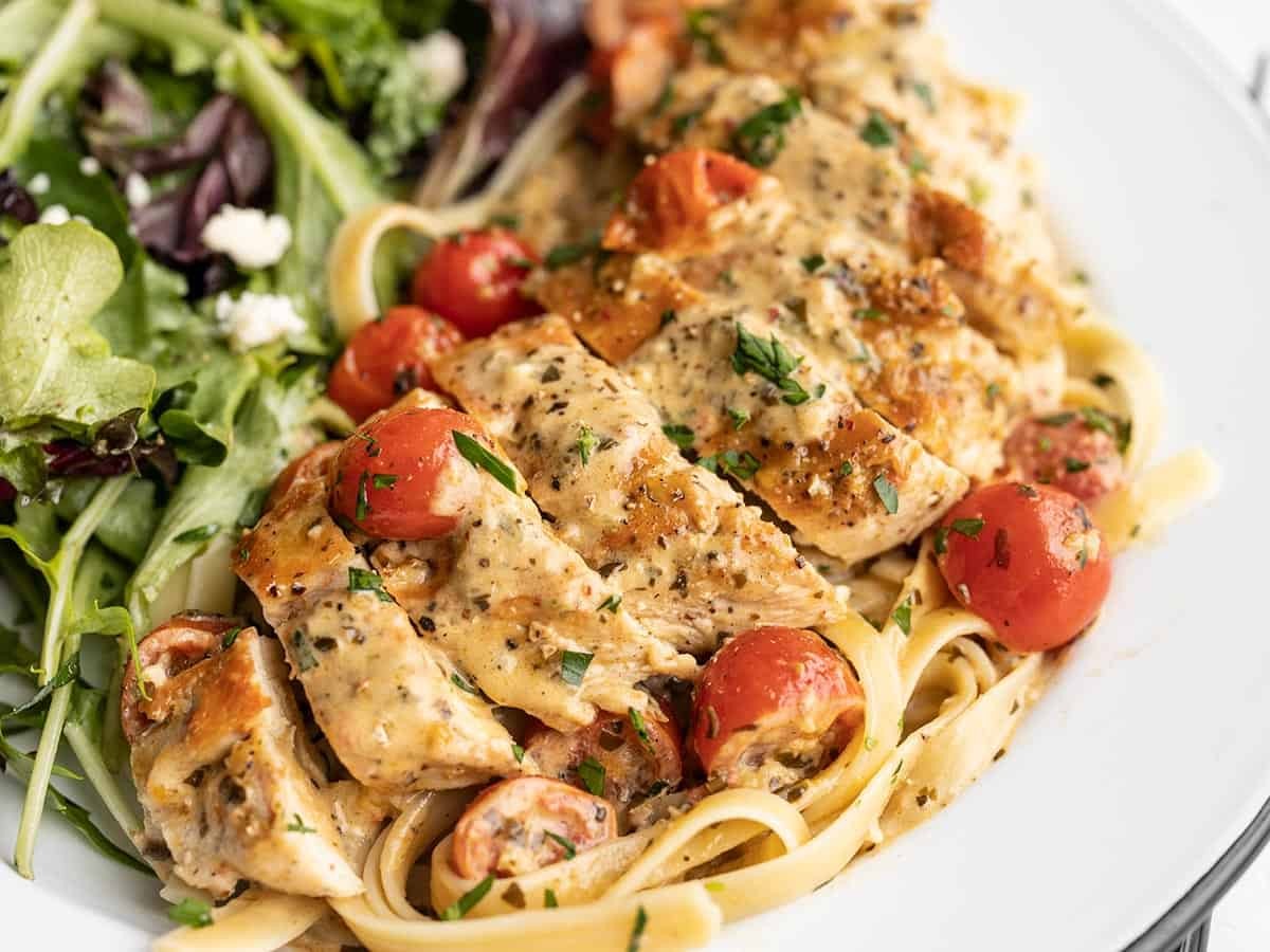 gorgeous plate of creamy pesto chicken, steaming, with fresh basil and cherry tomatoes, served with pasta