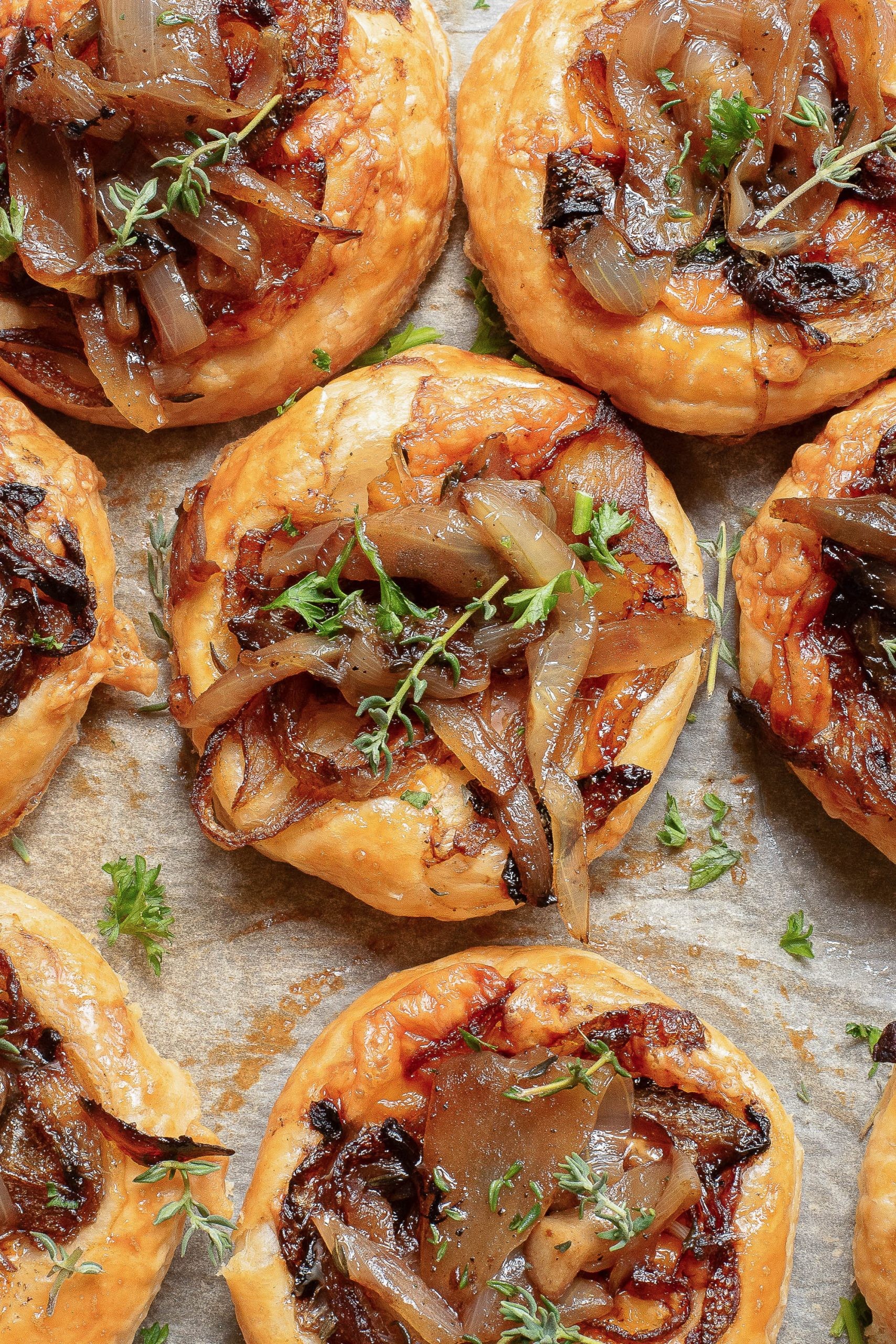 golden caramelized onion tartlets on a wooden board with fresh thyme