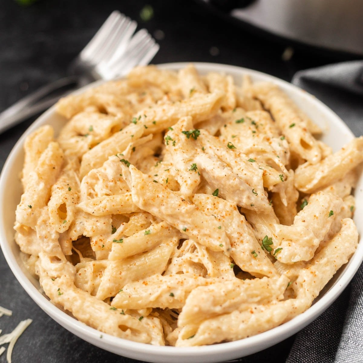 Creamy Cajun chicken pasta in a slow cooker, garnished with parsley