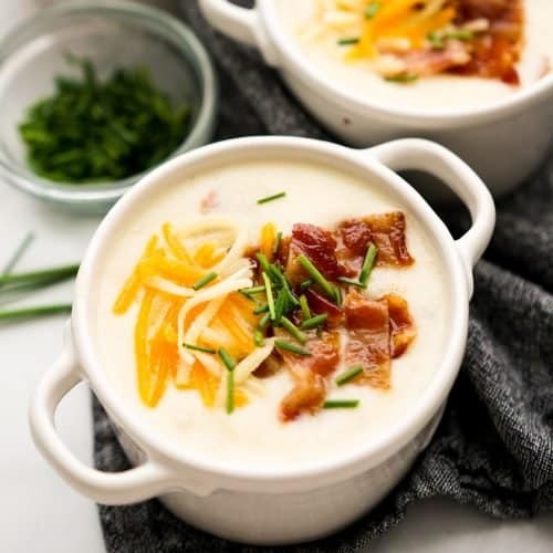 Delicious creamy potato soup in a rustic bowl, garnished with chives and crispy bacon bits, steam rising