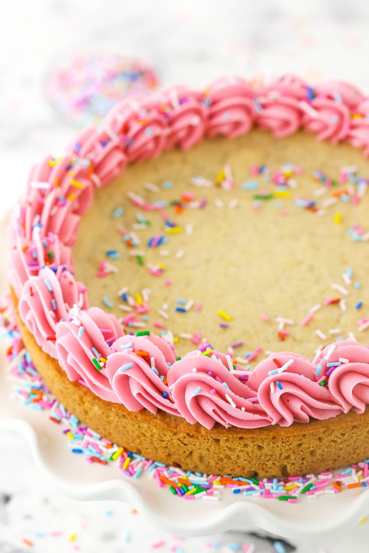 overhead shot of a beautifully decorated cookie cake with sprinkles and frosting