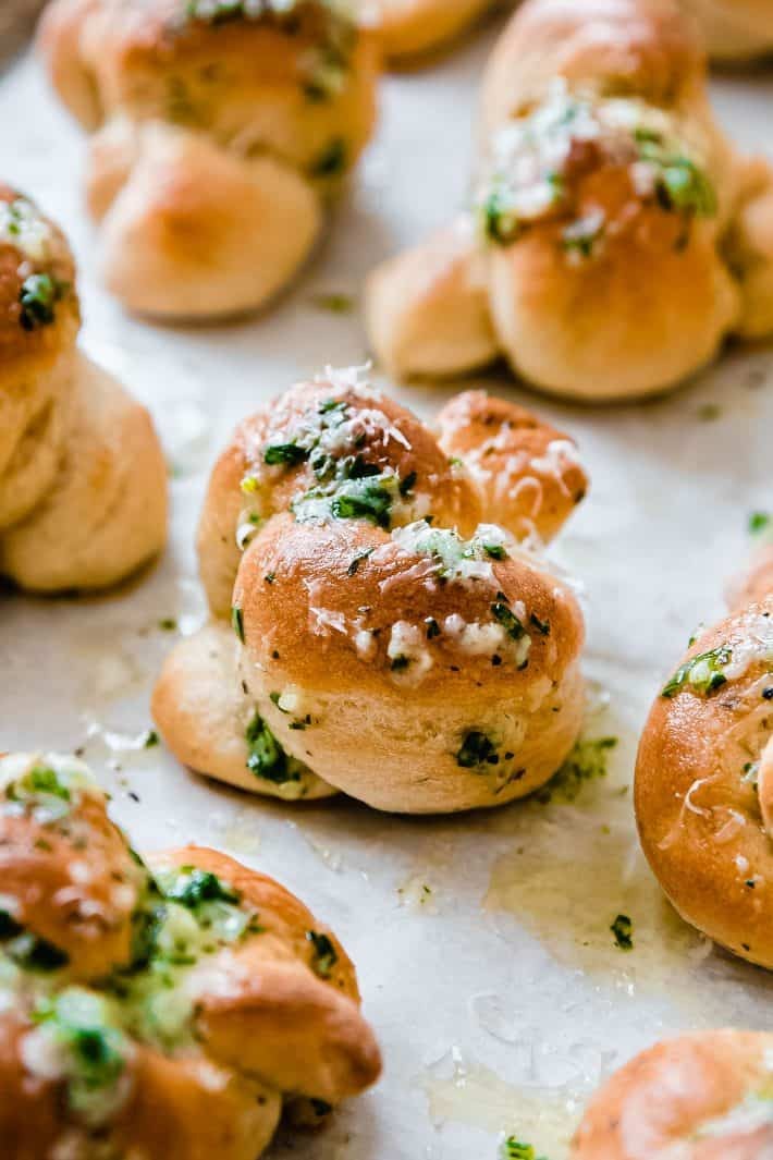Homemade Parmesan garlic knots fresh out of oven, golden brown with melted cheese and fresh parsley