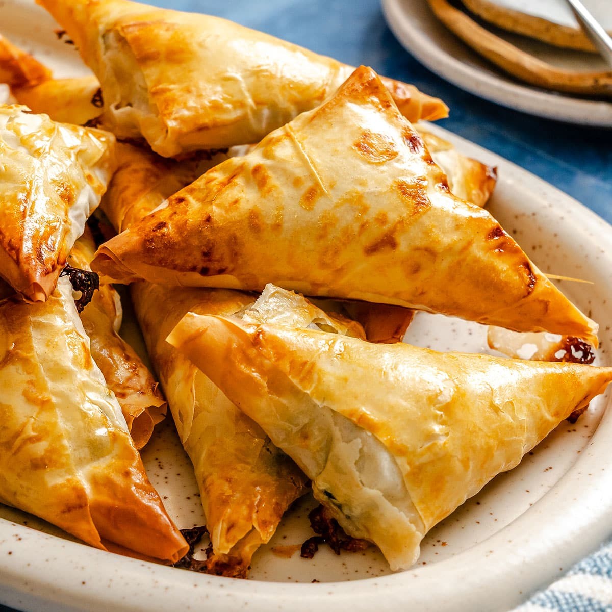 golden brown flaky spinach feta pastry triangles on a baking sheet, warm and inviting