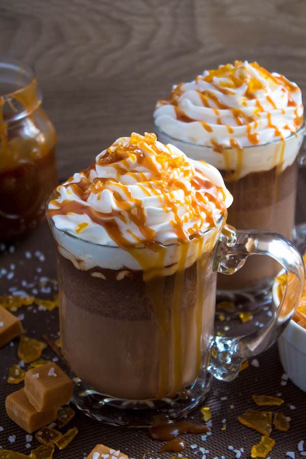 close-up salted caramel hot chocolate with whipped cream and rich caramel swirl, cozy winter setting, warm lighting