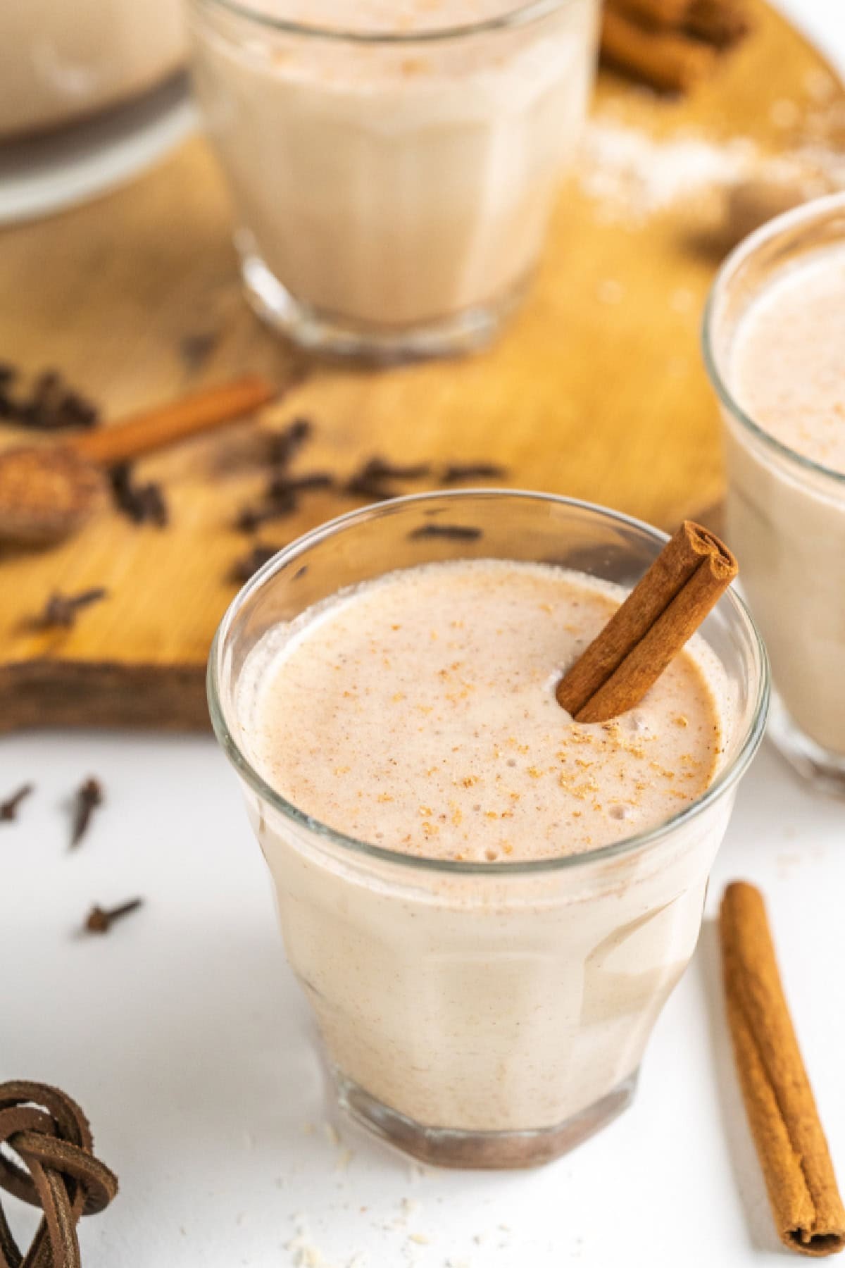 creamy coquito in a glass with cinnamon stick and nutmeg garnish, festive holiday party setting