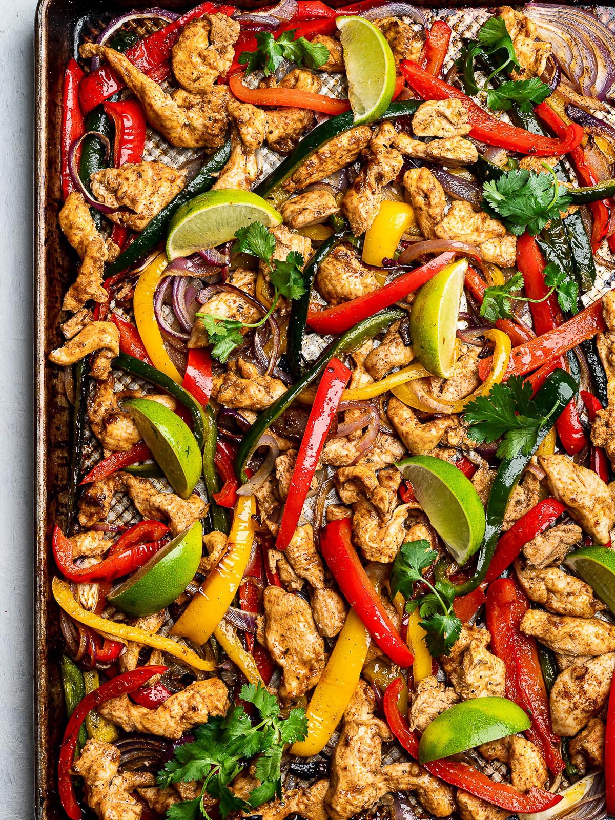 sheet pan fajitas with chicken, bell peppers, and onions, garnished with cilantro