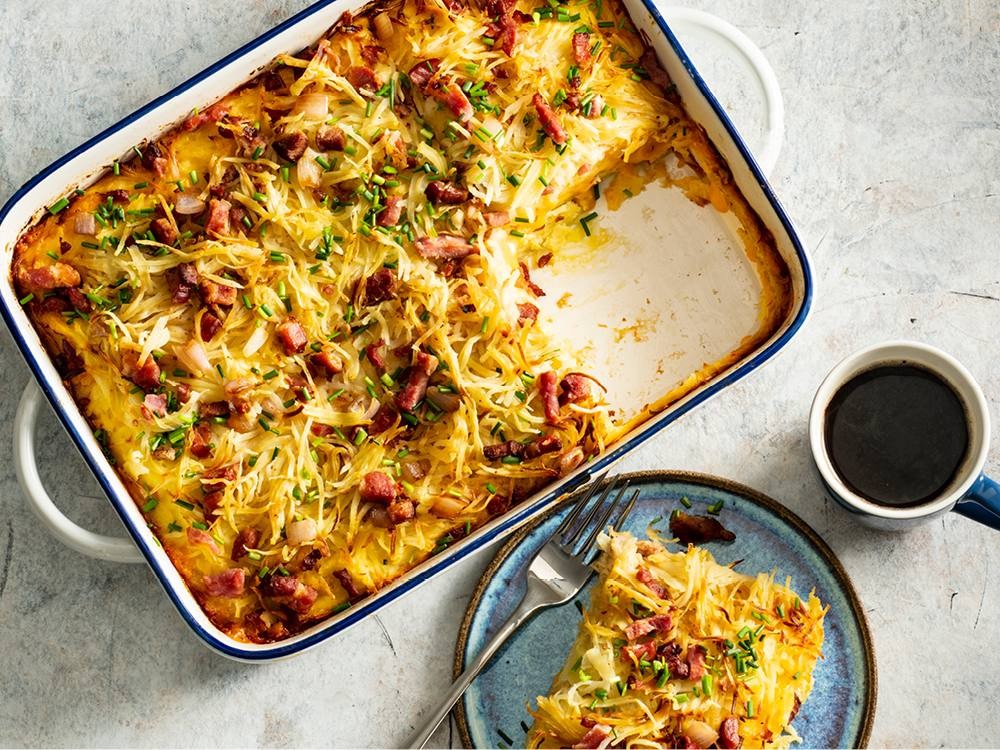 A beautifully golden-brown breakfast casserole with hash browns, eggs, cheese, and bacon, ready to serve in a rustic dish on a brunch table