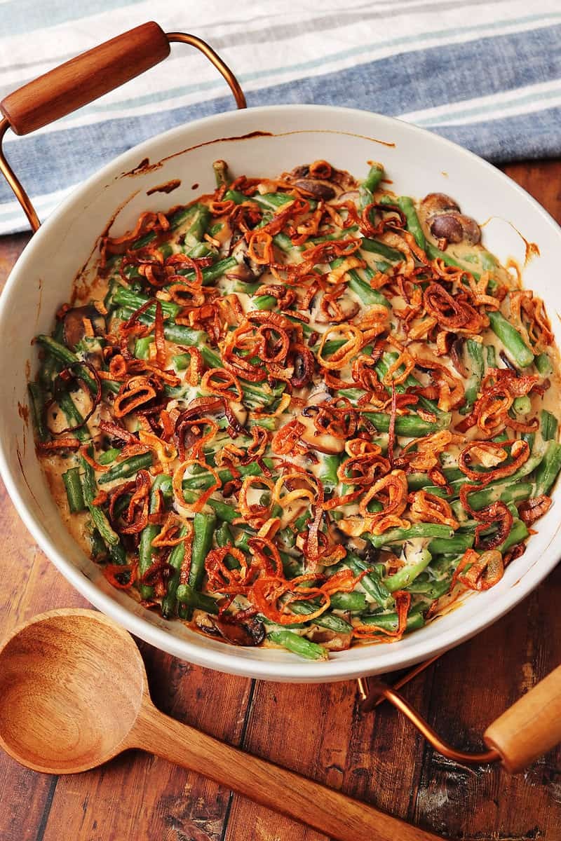 Homemade green bean casserole with crispy fried onions on a rustic table, close-up