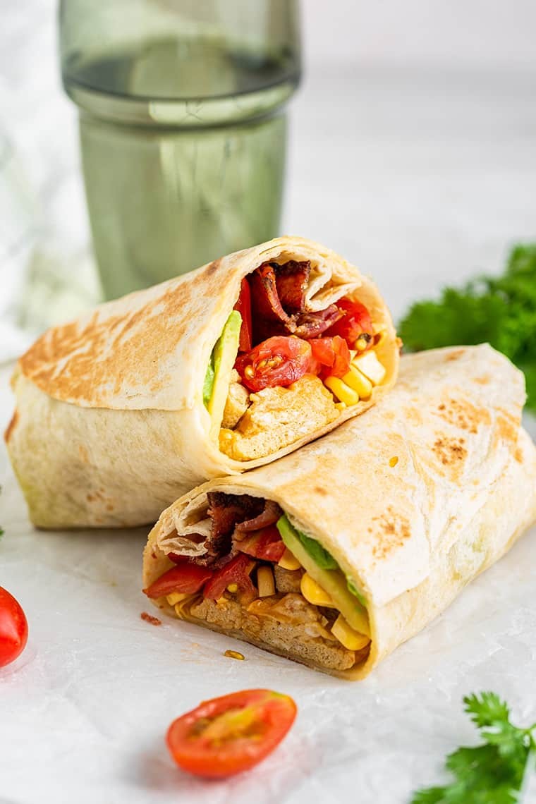 Vibrant, cheesy tangy breakfast burrito melt on a rustic plate, with a side of avocado