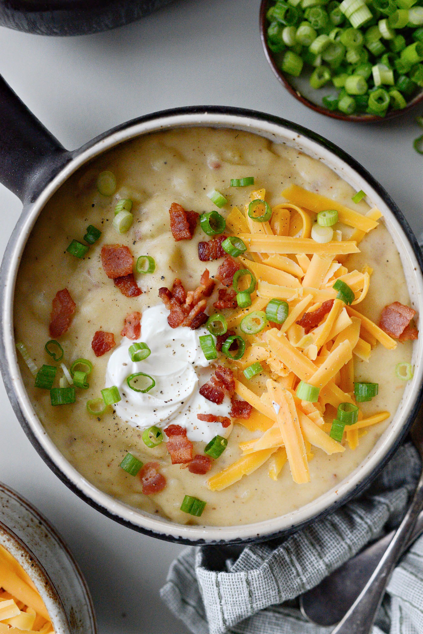 steaming bowl of herb loaded potato soup with crusty bread