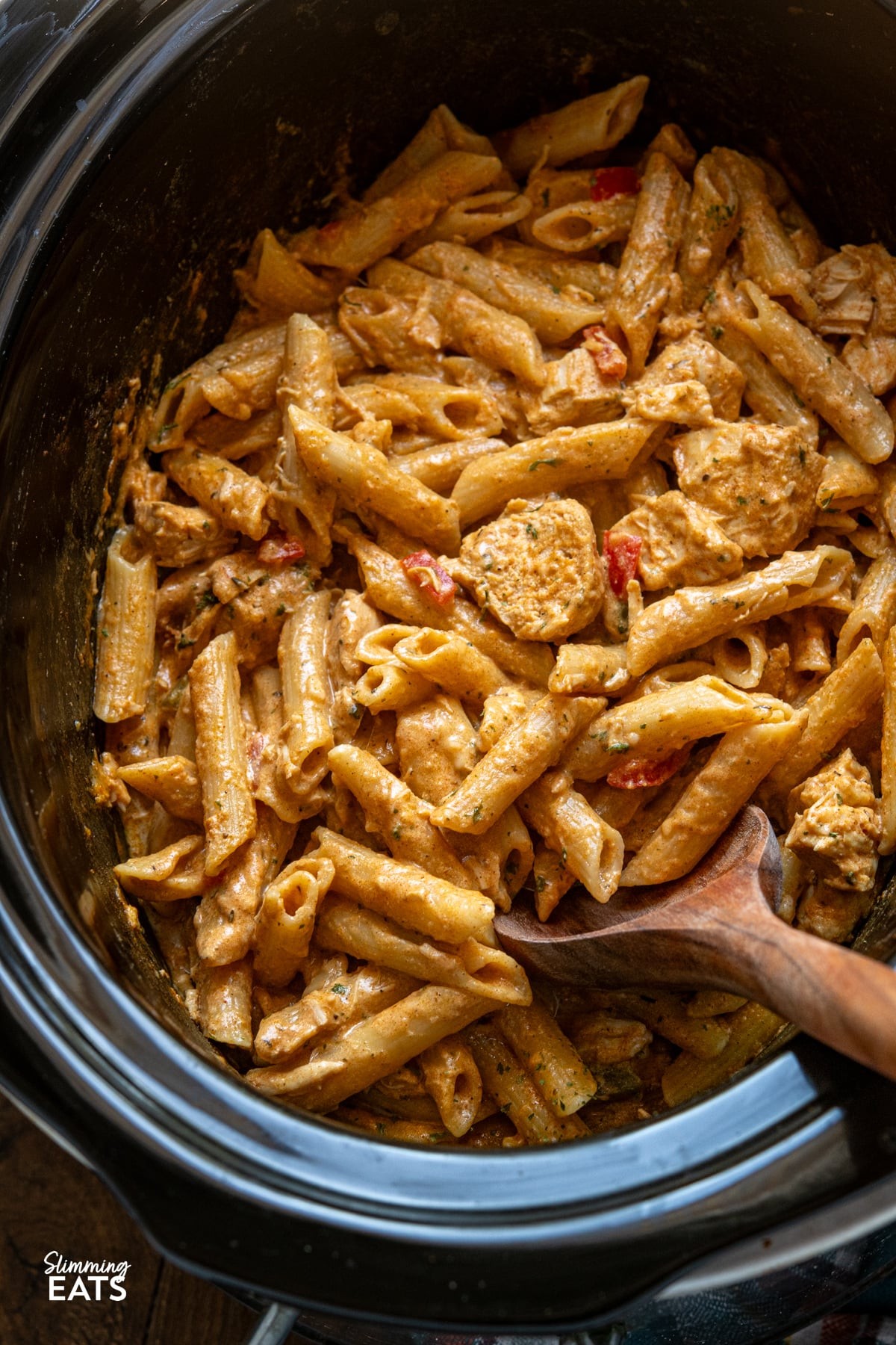 Creamy Cajun chicken pasta in a slow cooker, garnished with parsley, close-up