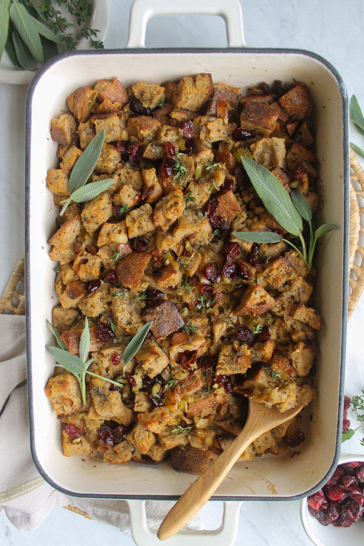 Thanksgiving maple cranberry stuffing in a ceramic baking dish, garnished with fresh herbs