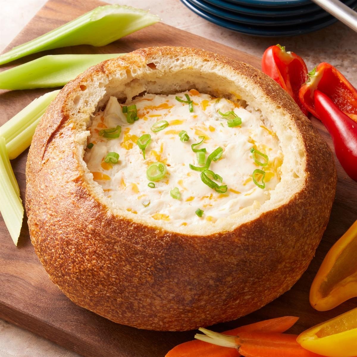 appetizing golden brown baked crab dip with melted cheese, served with crusty bread and crackers on a rustic wooden board, party setting