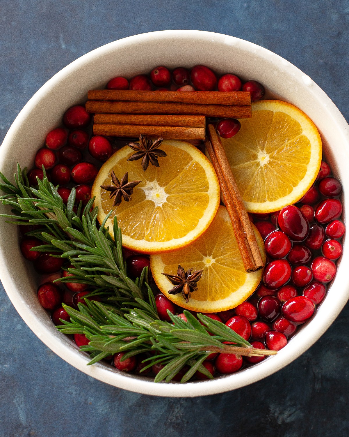 Cozy Christmas simmer pot with oranges, cranberries, cinnamon sticks, and star anise gently simmering, steam rising